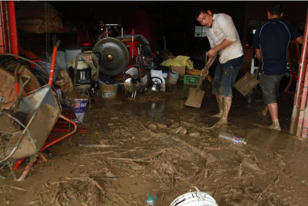 Taiwanese people scrape the mud off their house following flood and landslides triggered by typhoon Nanmadol in Laiyi, Pingtung County, Southern Taiwan, Monday, Aug. 29, 2011. Nanmadol slammed into Ta