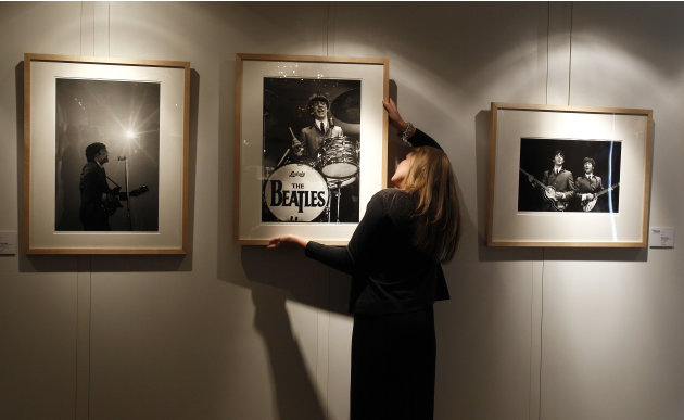 A Christie's employee hangs Mike Mitchell's photograph of The Beatles where his collection is being exhibited at a hotel in London, Friday, June 10, 2011. The previously unseen photographs by US photo