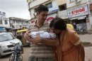 Fabbricatore holds his week-old daughter Gabriella, who is kissed by her maternal grandmother Patel, outside the Akanksha IVF centre in Anand town