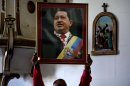 A Venezuelan embassy worker holds up a framed image of Venezuela's ailing President Hugo Chavez during the monthly Catholic service devoted to the sick at the Church of Our Lady of Regla, in Regla, across the bay from Havana, Cuba, Tuesday, Jan. 8, 2013. Venezuela's government said Monday, Chavez is in a "stable situation" in a Cuban hospital receiving treatment due to a severe respiratory infection. The update came as other government officials reiterated their stance that the president need not be sworn in for a new term as scheduled this Thursday and could instead have his inauguration at a later date. (AP Photo/Ramon Espinosa)
