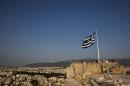 Greek flag flutters in the wind as tourists visit the archaeological site of the Acropolis hill in Athens, Greece
