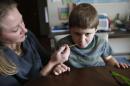 In this Jan. 1, 2015, photo, Nicole Gross uses an oral syringe to give her son Chase his daily dose of a medical marijuana oil, known as Charlotte's Web, at their home in Colorado Springs, Colo. They moved to Colorado from Chicago about a year ago to legally treat Chase, who used to have hundreds of seizures per day. (AP Photo/Brennan Linsley)