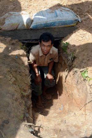 A Cambodian villager walks out from a bunker he dug …