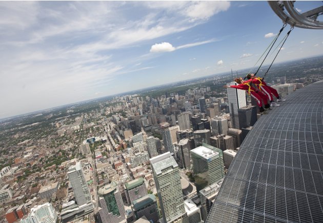 Reporters lean back, 1,168 feet over Toronto's downtown,  while participating in a media preview of the new EdgeWalk attraction on the CN Tower Wednesday, July 27, 2011. Participants are strapped into