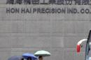 People holding umbrellas walk in front of the headquarters of Hon Hai, which is also known by its trading name Foxconn, in Tucheng, New Taipei city
