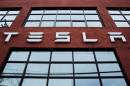 FILE PHOTO: A Tesla logo hangs on a building outside of a Tesla dealership in New York