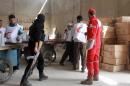 A rebel fighter watches as workers from the Syrian Red Crescent and United Nations High Commissioner for Refugees (UNHCR) arrive with aid at the rebel controlled Garage al-Hajz checkpoint near Aleppo, on April 8, 2014