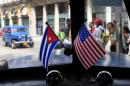 In this March 22, 2013 file photo, miniature flags representing Cuba and the U.S. are displayed on the dash of an American classic car in Havana, Cuba. The Obama administration is putting a large dent in the U.S. embargo against Cuba as of Friday, significantly loosening restrictions on American trade and investment. The new rules also open up the communist island to greater American travel and allow U.S. citizens to start bringing home small amounts of Cuban cigars after more than a half-century ban. (AP Photo/Franklin Reyes, File)