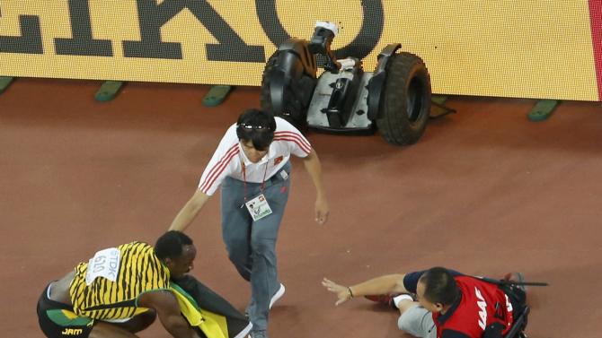 Winner Bolt of Jamaica crouches after being hit by a cameraman on a Segway after competing at the men&#39;s 200 metres final during the 15th IAAF World Championships at the National Stadium in Beijing