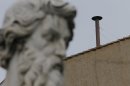 A statue dwarfs the chimney on the roof of the Sistine Chapel where cardinals will gather to elect the new pope during the conclave at the Vatican, Monday, March 11, 2013. (AP Photo/Dmitry Lovetsky)