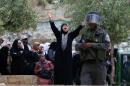 A Palestinian woman shouts behind an Israeli border guard as Muslim worshippers wait to have their documents checked at the entrance of the Al-Aqsa mosque compound in Jerusalem, on April 20, 2014