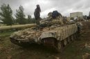 Free Syrian Army fighters inspect a tank after the fighters said they fought and defeated government troops in Al-Latameneh