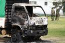 Armed police walk past a truck set on fire by attackers who raided Gamba police station at the Kenyan coast