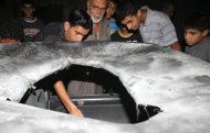 Palestinians inspect the wreckage of a car after it was hit by an Israeli missile strike in Beit Lahia, northern Gaza Strip, Sunday, Aug. 21, 2011. (AP Photo/Hatem Moussa)