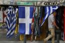 A man passes a kiosk selling Greek flags in central Athens, Saturday, July 4, 2015. Whether Greeks decide in Sunday's referendum to accept their lenders' bailout deal or reject it, the government's hold on power may be shakier than its brash prime minister has calculated, analysts say. (AP Photo/Petros Karadjias)