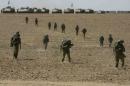 Israeli soldiers from the Nahal Infantry Brigade walk across a field near central Gaza Strip