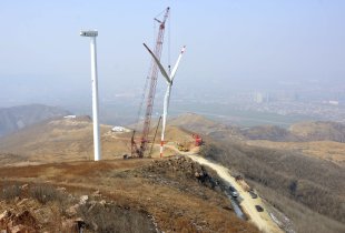 The rotor blades of a wind turbine is lifted by a crane at a construction site of a wind power plant in Yiyang, Henan province, China. (Reuters)