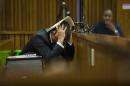 Oscar Pistorius covers his head with his hands and a notebook as he listens to forensic evidence during his trial in court in Pretoria, South Africa, Thursday March 13, 2014. Pistorius is charged with the shooting death of his girlfriend Reeva Steenkamp on Valentines Day in 2013. (AP Photo/Alet Pretorius, Pool)