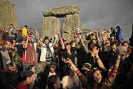 Un grupo de personas celebra que las nubes permitieron el paso de los rayos del sol un par de horas después del amanecer durante el solsticio de verano en Stonehenge, Inglaterra, el martes 21 de junio del 2011. (Foto AP/Matt Dunham)