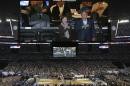 Former president George W. Bush and wife Laura are seen with former president Bill Clinton, left, on the overhead scoreboard during the national anthem before the NCAA Final Four tournament college basketball championship game between Connecticut and Kentucky, Monday, April 7, 2014, in Arlington, Texas. (AP Photo/Tony Gutierrez)