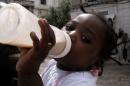 A girl drinks milk from a feeding bottle on a street in Lisbon
