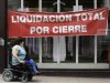 A woman in a wheelchair passes the shop window of a clothing store in Pontevedra
