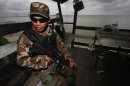 A member of Royal Malaysian Navy's Naval Special Warfare Forces guards the beach near an area where armed men are holding off, in Felda Sahabat plantation farm