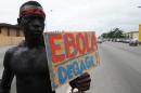 A man holds a placard reading "Ebola, go away" as members of the artist group "'Be Kok Spirit'' march to raise awareness on the Ebola virus, on August 19, 2014 in Abidjian