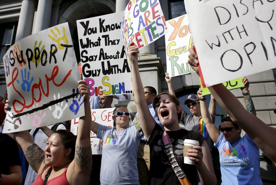 Katarina Ezikovich, of Warren, R.I., center right front row, displays a placard and shouts slogans with other demonstrators in support of same-sex marriage in front of City Hall, in Providence, Thursday, Aug. 1, 2013 Gay marriage became legal in Rhode Island and Minnesota at 12:01 a.m. Thursday. Officials around Rhode Island began issuing licenses when offices opened at 8:30 a.m. (AP Photo/Steven Senne)