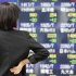 A woman watches an electronic stock board of a securities firm in Tokyo, Thursday, May 16, 2013. Asian stock markets were mixed Thursday following dour European economic data that dampened hopes of a recovery there anytime soon. However, losses were limited by another record session on Wall Street. (AP Photo/Koji Sasahara)
