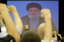 Lebanese Shiite men raise their fists up as they listen to a speech via videolink by Hezbollah leader Hassan Nasrallah