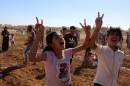In this Friday, Sept. 26, 2014 photo, children from Kobani celebrate as Kurds from Turkey and Syria break down the barbed wire at the Turkey-Syria border near Suruc, Turkish President Recep Tayyip Erdogan said Friday that a "no-fly zone" should be created in Syria to protect part of it from attacks by Syria's air force. In his comments to reporters on his return from the U.N. General Assembly in New York, Erdogan did not specify where such a zone should be located. (AP Photo/Burhan Ozbilici)