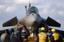 Technicians stand next to a French Navy Rafale fighter jet onboard the French Navy aircraft carrier Charles de Gaulle, operating in the Gulf, on February 23, 2015