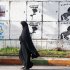 A woman walks past electoral paintings representing political parties in Casablanca, Morocco, Thursday, Nov. 24, 2011. Moroccans head to polls to elect a new parliament Friday after the king brought forward elections in response to Arab Spring demonstrations over the past nine months. (AP Photo/Abdeljalil Bounhar)