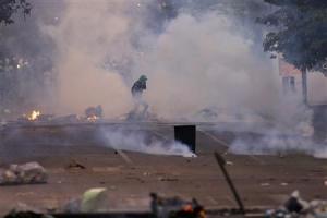 An anti-government protester runs through teargas during …