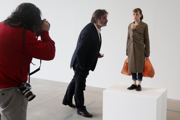 A visitor looks at a sculpture entitled "Woman with Shopping, 2013" by artist Ron Mueck during his exhibition at the Fondation Cartier pour l'art contemporain in Paris