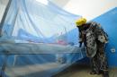 A woman looks at her sick child laying under a mosquito net in a hospital on April 24, 2015 in Abidjan