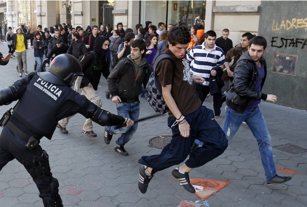 A policeman uses his baton against students protesting against spending cuts in public education in Barcelona