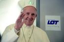 Pope Francis waves during a press conference on the plane after his visit to Krakow for the World Youth Days