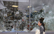 A woman walks past a damaged supermarket in Ealing, west London, after a night of rioting, Tuesday, Aug. 9, 2011. In London, groups of young people rampaged for a third straight night, setting buildings, vehicles and garbage dumps alight, looting stores and pelting police officers with bottles and fireworks into early Tuesday. The spreading disorder was an unwelcome warning of the possibility of violence during London's 2012 Summer Olympics, less than a year away. (AP Photo/Lefteris Pitarakis)