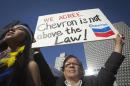 A protester holds up a sign as he demonstrates against Chevron's Racketeer Influenced and Corrupt Organizations trial in New York
