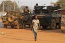 A woman walks past French peacekeeping troops in street of the capital Bangui