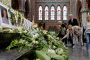 People place flowers under near photographs of MH17 victims on August 17, 2014 during a memorial service in Hilversum, Netherlands