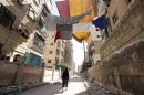 File picture of a Free Syrian Army fighter walking along a street where curtains are hung as protection from snipers loyal to Syria's President al-Assad in Aleppo's Saif al-Dawla district