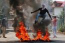 A man in a balaclava jumps over burning debris during a protest against the recent killings in Kashmir, in Srinagar