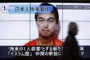 Man walks past screens displaying TV news program showing image of Goto, one of two Japanese citizens taken captive by Islamic State militants, on a street in Tokyo