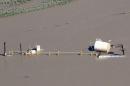 An oil storage tank on a well pad lies toppled by flood waters in Weld County, Colorado
