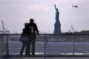 Tourists pause to view the Statue of Liberty from a Liberty Island ferry boat at Battery Park in New York