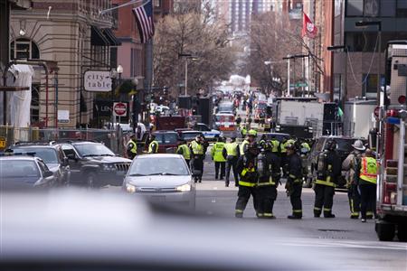 Boston Police and Firemen stand by at the scene after explosions reportedly interrupted the running of the 117th Boston Marathon in Boston