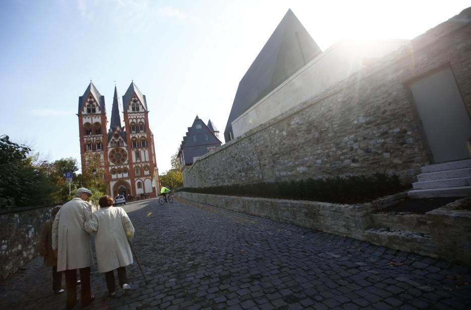 Elderly couple walks past the bishop's residence with the bishop's private chapel in Limburg